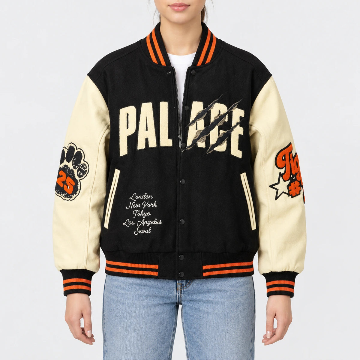 Women’s black wool varsity jacket with cream leather sleeves, orange striped rib trim, chenille patches and snap front