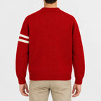 Men's red knit cardigan jacket featuring a skull and crossbones patch, cream sleeve stripes, button front closure, ribbed cuffs and hem, styled with khaki chinos.